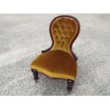A Victorian mahogany framed nursing chair with button back old gold upholstery the supports