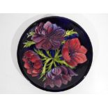 Moorcroft - a large Moorcroft pottery charger, decorated with anemone on a blue ground,