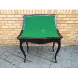 An ebony serpentine fronted games table the flip top opening to reveal a green baize surface,