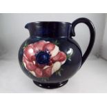 Moorcroft - A large Moorcroft pottery milk jug, decorated with anemone on a blue ground,