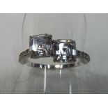 A white metal ring set with two stones and stone chips to the shank size R