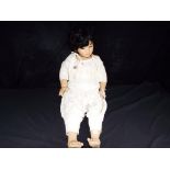 An unusual and detailed hand painted porcelain faced doll dressed in white cotton clothes with