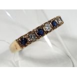 A hallmarked 9 carat gold half eternity ring set with seven stones comprising four sapphires and