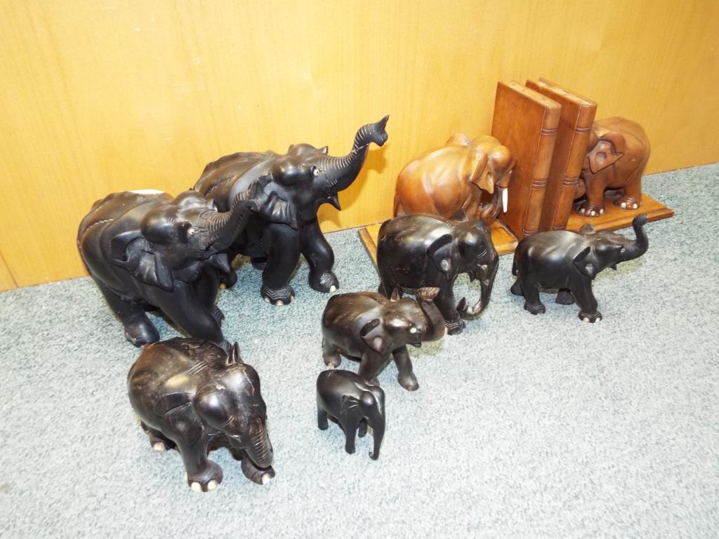 A herd of ebonised elephants and a carved wooden treen elephants in a form of bookends [qty].