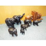 A herd of ebonised elephants and a carved wooden treen elephants in a form of bookends [qty].