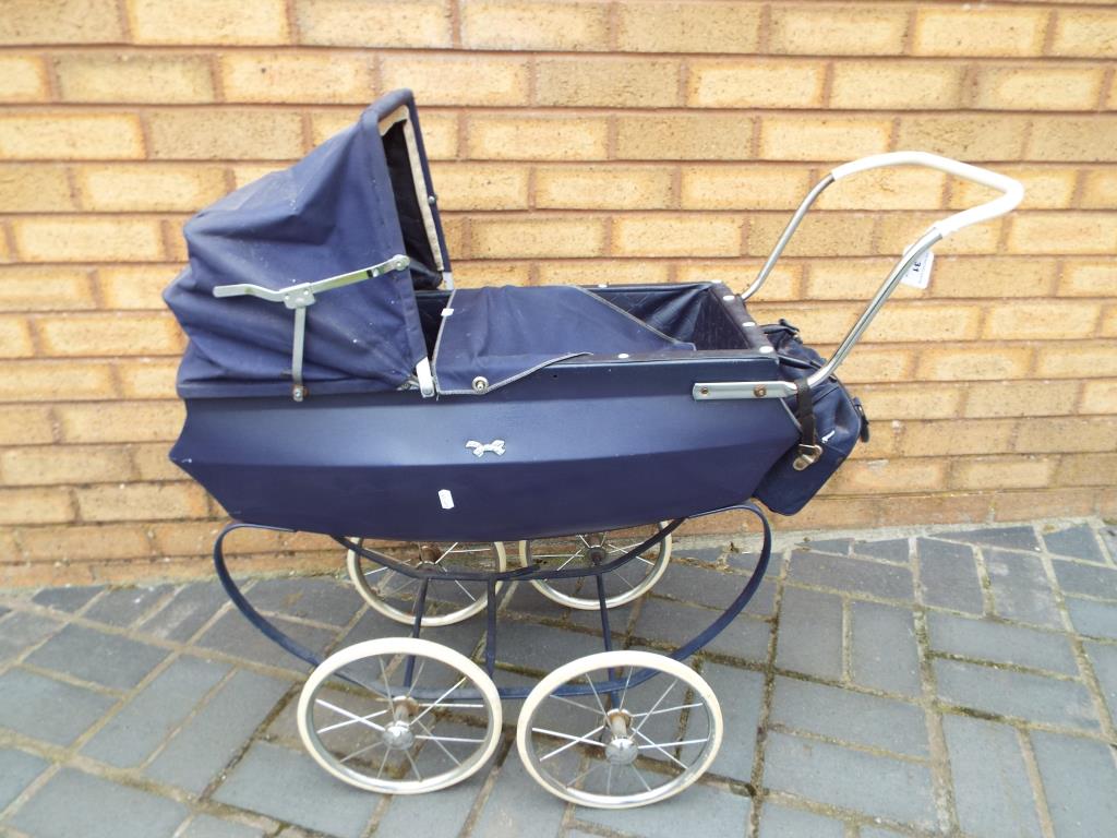 A vintage Silver Cross style pushchair with a hood cover and accessories bike