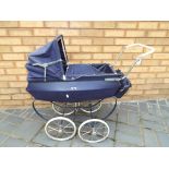 A vintage Silver Cross style pushchair with a hood cover and accessories bike