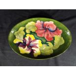 Moorcroft - a Moorcroft Pottery oval tray decorated with hibiscus on a green ground,
