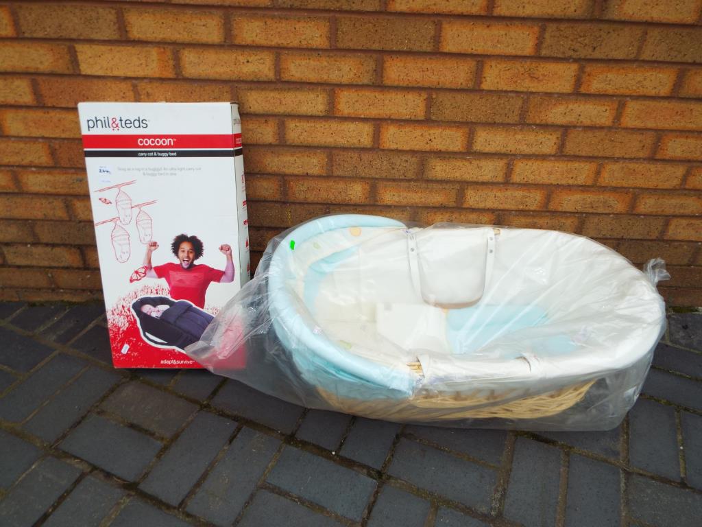 A wicker Moses basket sealed in original packaging with a Phil & Teds cocoon carry cot and buggy