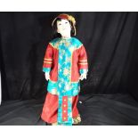 An unusual and detailed hand painted porcelain Oriental doll dressed in Oriental clothing, on stand,