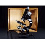 A large vintage microscope contained in wooden protective carry case