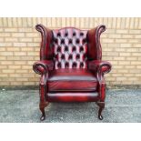 An oxblood button back Chesterfield armchair with studded arm fronts,