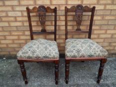 A pair of highly carved dining chairs wi