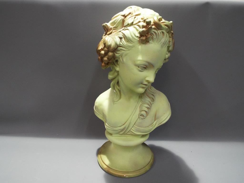 A plaster bust of a young lady with grapes and leaves in her hair,