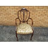A highly carved shield back mahogany upholstered occasional chair,