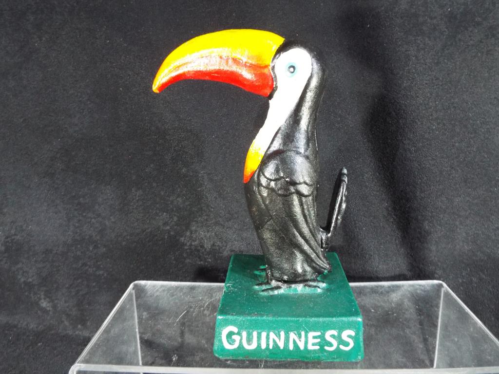 A cast figure depicting a toucan and marked 'Guinness' to the green base, 19.