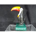 A cast figure depicting a toucan and marked 'Guinness' to the green base, 19.