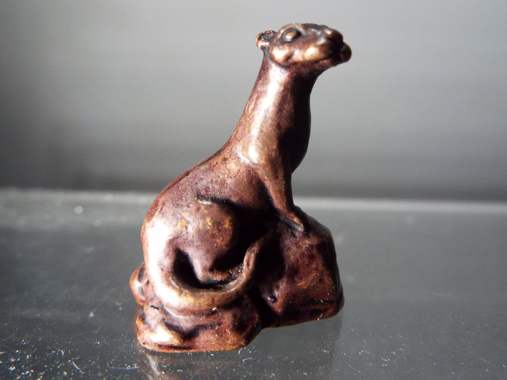 A diminutive hot cast bronze in the form of an otter seated on rocks.