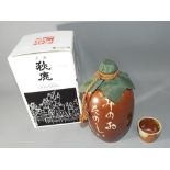 A boxed Oriental stoneware jug, sealed with content and supplied with small cup.
