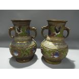 A pair of brass cloisonne twin handled vases depicting birds,