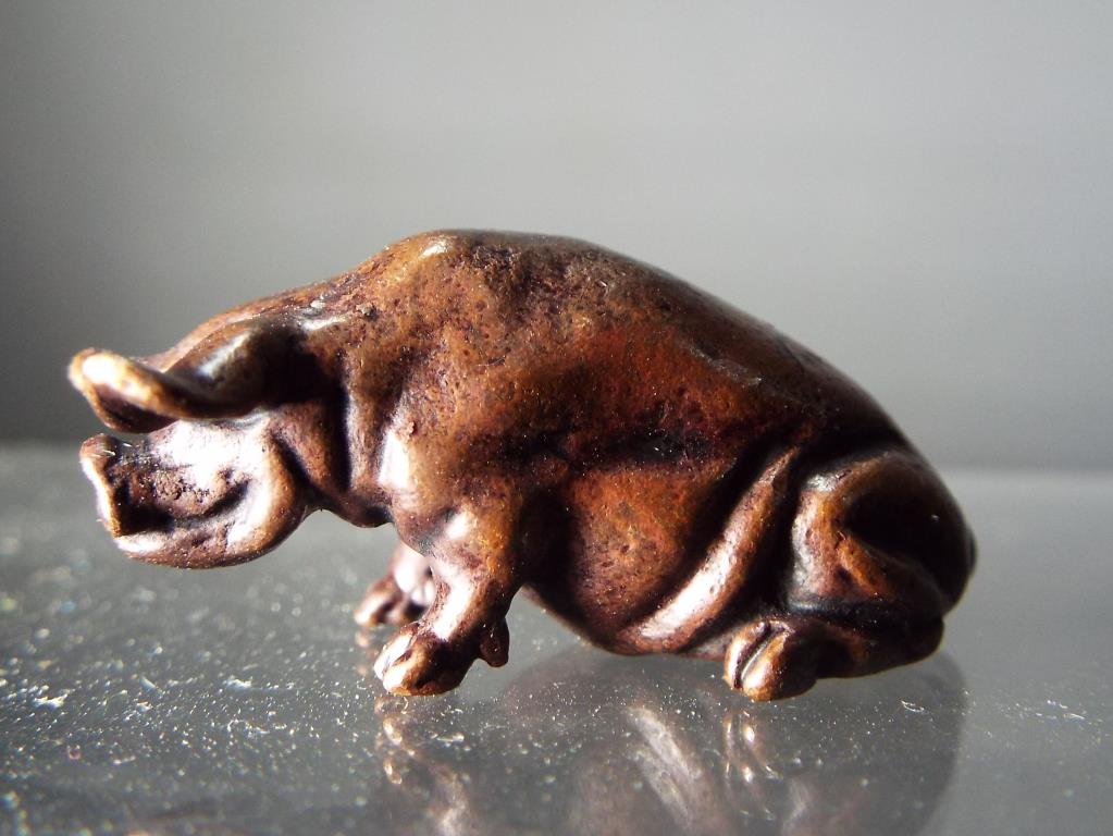 A diminutive hot cast bronze study of a seated pig.