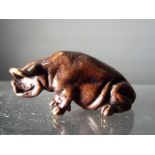 A diminutive hot cast bronze study of a seated pig.