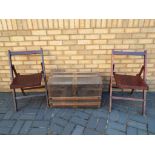 A wooden and metal travel trunk with two fold away chairs.