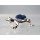 A silver frog pin cushion.