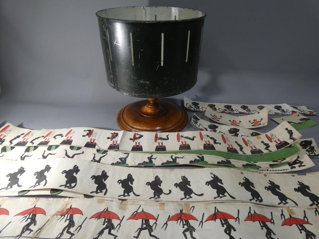A Zoetrope or Wheel of Life on a turned wooden base with eleven paper animation panels [3 ripped],