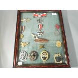A glass cased collection of fourteen medals and badges bearing Third Reich emblems,