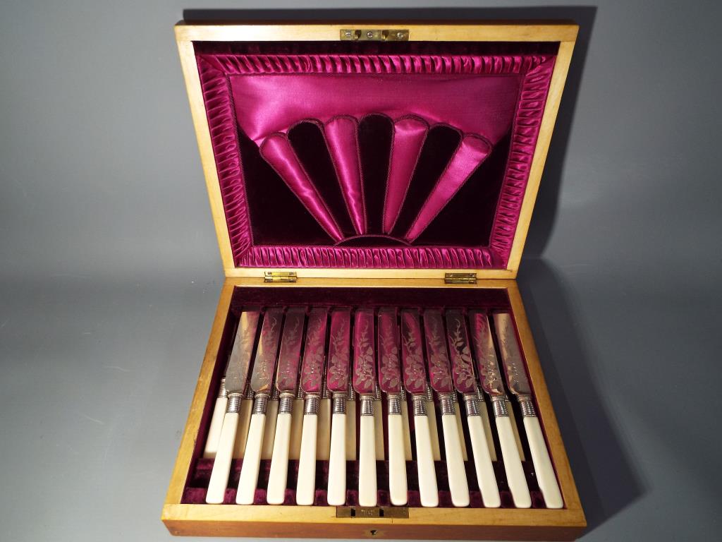 An Art Deco canteen of 12 pairs of fruit knives and forks with chased foliate decoration