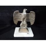 A white metal figure depicting eagle and swastika on a marble base,