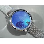 A modern stainless unused wristwatch with a silhouette scene