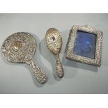 Three silver hallmarked items to include photograph frame, dressing table mirror and brush,