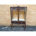 A good quality display cabinet raised on four supports,