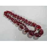 A faceted graduated cherry bakelite amber necklace, largest bead 3.