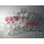 A quantity of drinking glasses to include cranberry cut to clear, Harrods branded,