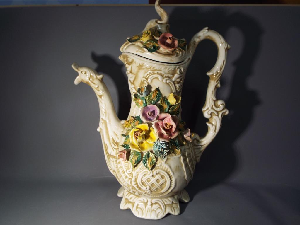 A large Capodimonte Pitcher with applied floral decoration, dragon spout and a cover,