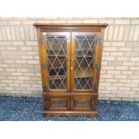 A glass fronted twin door Old Charm bookcase approximately 128 cm x 80 cm x 29 cm.