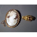 A yellow metal cameo brooch with safety chain and a further yellow metal stone set brooch.