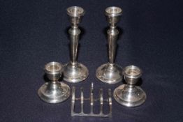 Silver five bar toast rack and two pairs of silver candlesticks