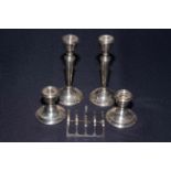 Silver five bar toast rack and two pairs of silver candlesticks