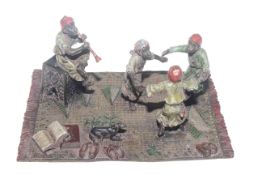 A cold painted bronze group, three children dance to the tune of a flautist,