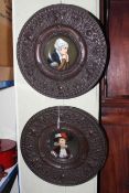 Pair of porcelain portrait plaques in embossed metal frames,