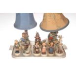 Two Hummel table lamps with shades and seven Hummel figures