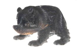 Black wooden carved grizzly bear carrying a fish in its mouth,