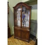 Arched top mahogany display cabinet having two glazed panel doors above two inlaid oval panel doors