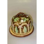 Majolica style stilton cover and stand decorated with garden scene,