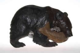 Carved wood grizzly bear carrying a fish it its mouth,