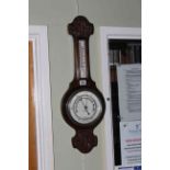 Carved oak barometer-thermometer with silvered dial.